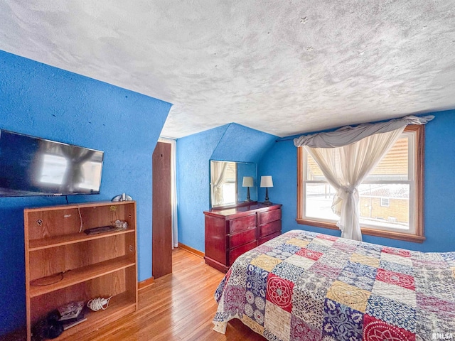 bedroom featuring lofted ceiling, a textured ceiling, and light hardwood / wood-style floors