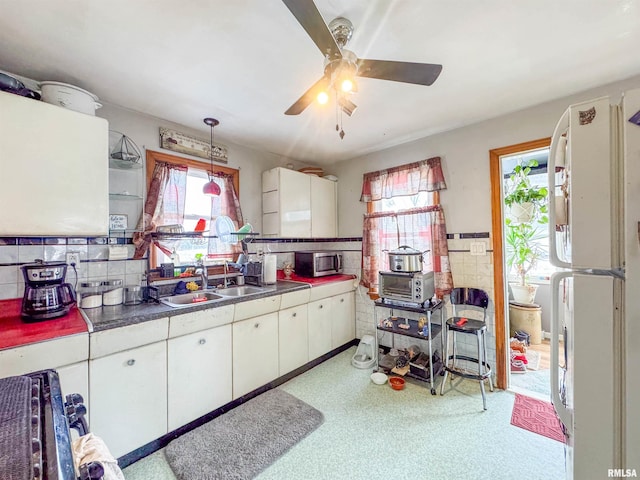 kitchen with sink, white fridge, pendant lighting, decorative backsplash, and white cabinets