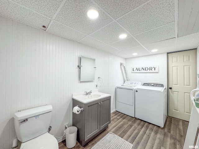 washroom featuring separate washer and dryer, sink, hardwood / wood-style flooring, and wood walls