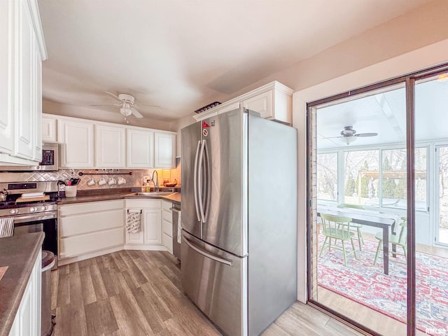 kitchen featuring appliances with stainless steel finishes, white cabinetry, sink, backsplash, and light wood-type flooring