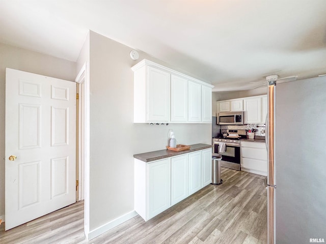 kitchen featuring tasteful backsplash, light wood-type flooring, white cabinets, and appliances with stainless steel finishes