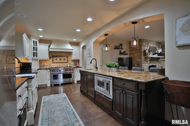 kitchen with sink, premium range hood, appliances with stainless steel finishes, white cabinets, and decorative light fixtures