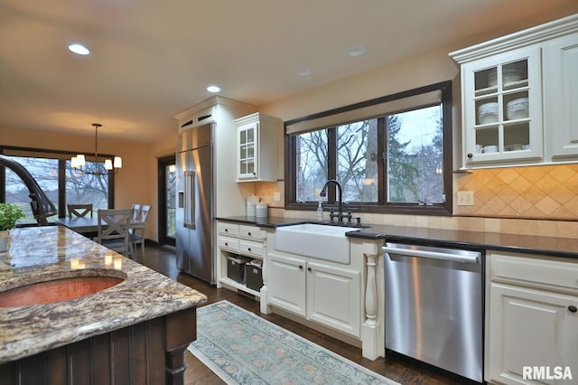 kitchen with white cabinetry, sink, stainless steel appliances, and dark stone counters