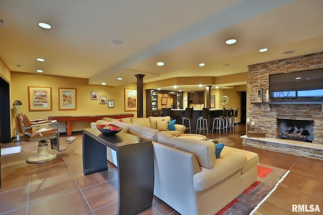 living room featuring tile patterned flooring, indoor bar, a fireplace, and ornate columns