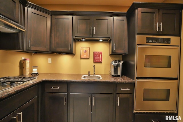 kitchen with dark brown cabinetry, sink, wall chimney range hood, and stainless steel appliances