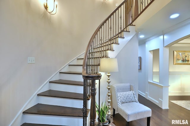 staircase featuring a towering ceiling and wood-type flooring