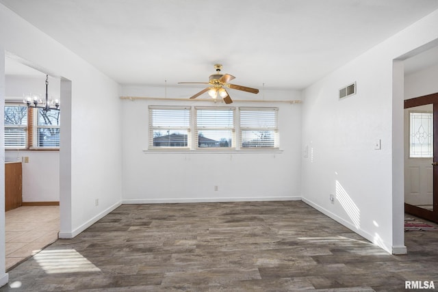 empty room with ceiling fan with notable chandelier and dark hardwood / wood-style flooring