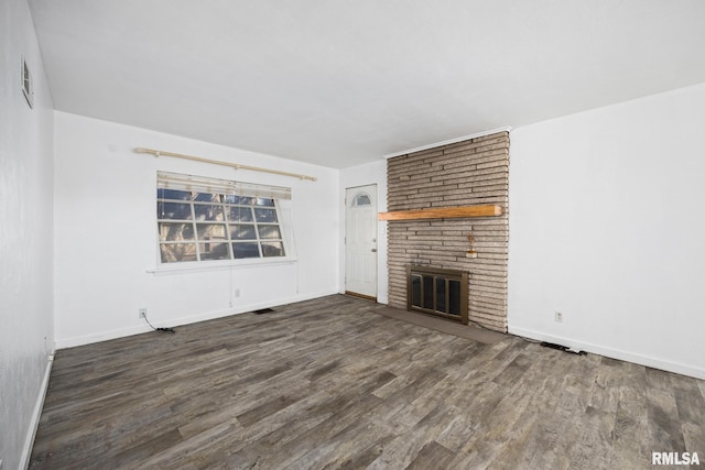 unfurnished living room with a brick fireplace and dark hardwood / wood-style floors