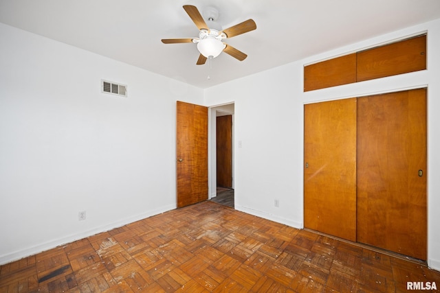 unfurnished bedroom with ceiling fan, a closet, and dark parquet floors