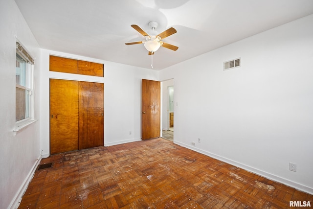 unfurnished bedroom with dark parquet floors and ceiling fan