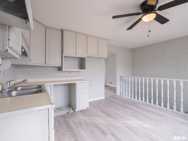 kitchen featuring sink, white cabinetry, built in desk, light hardwood / wood-style flooring, and ceiling fan