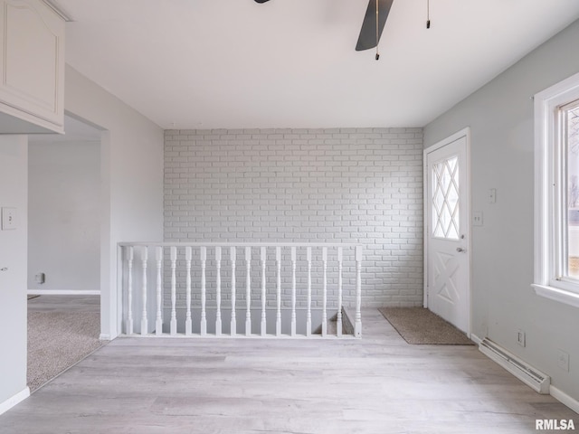 spare room featuring ceiling fan, light hardwood / wood-style flooring, and a baseboard heating unit