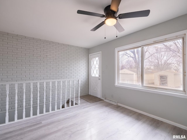 unfurnished room with brick wall and light wood-type flooring