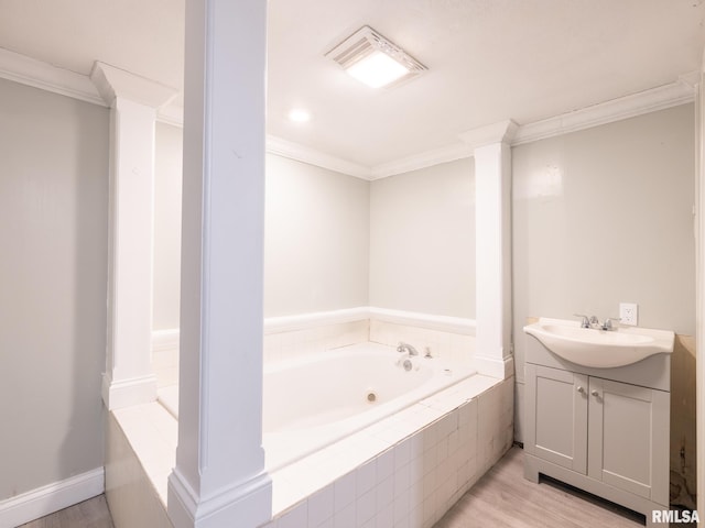 bathroom with ornate columns, wood-type flooring, vanity, a relaxing tiled tub, and crown molding