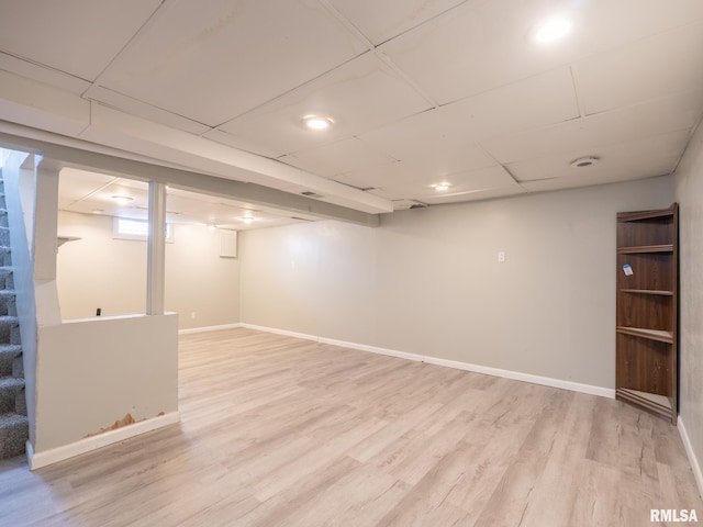 basement with a drop ceiling and hardwood / wood-style flooring