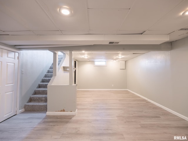 basement featuring a drop ceiling and wood-type flooring