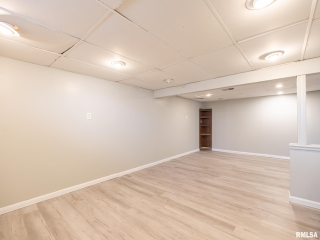 basement with a drop ceiling and light wood-type flooring