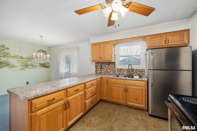 kitchen featuring stainless steel refrigerator, kitchen peninsula, sink, and hanging light fixtures