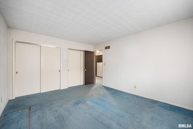 unfurnished bedroom with carpet floors and two closets