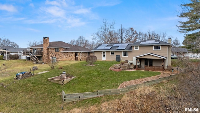 back of house featuring a yard, a deck, central air condition unit, and solar panels