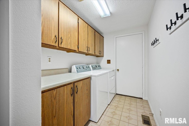 clothes washing area featuring cabinets, separate washer and dryer, and a textured ceiling