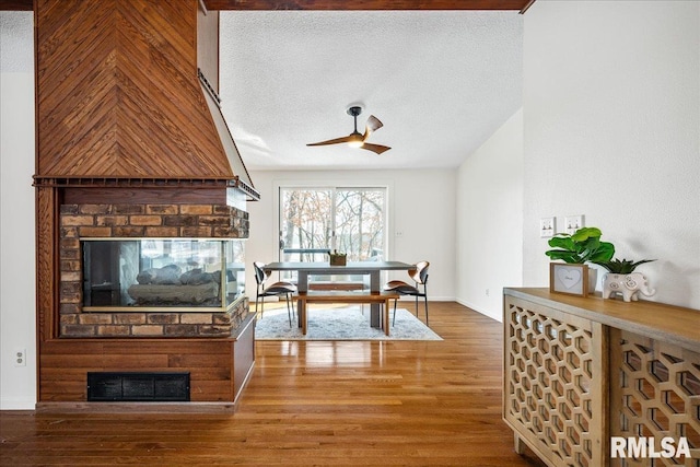 interior space featuring hardwood / wood-style flooring, ceiling fan, a brick fireplace, and a textured ceiling