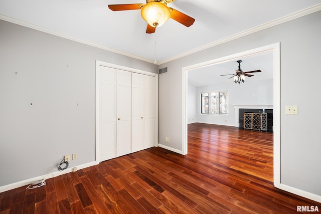 interior space with ornamental molding, dark wood-type flooring, ceiling fan, and a closet