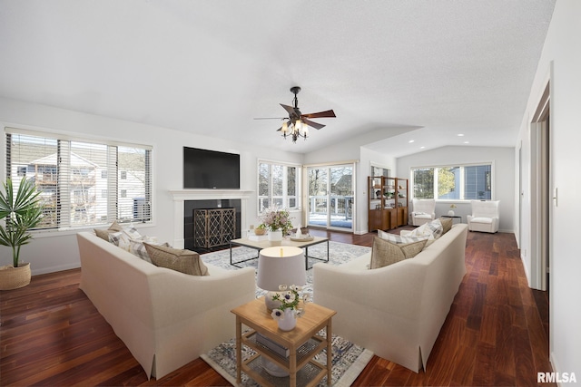 living room with dark wood-type flooring, vaulted ceiling, a tile fireplace, and ceiling fan