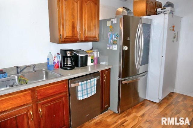 kitchen featuring stainless steel appliances, sink, and light hardwood / wood-style floors