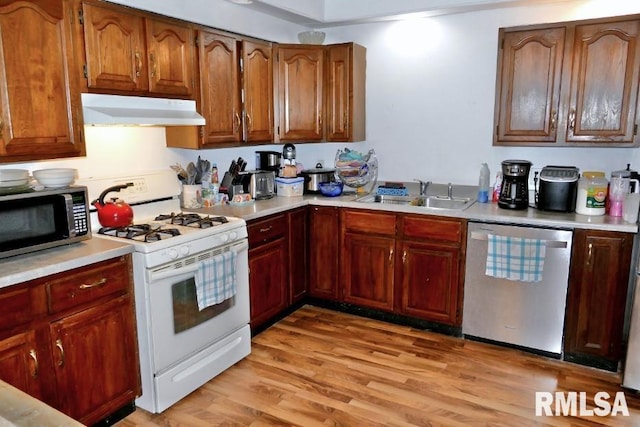 kitchen with appliances with stainless steel finishes, light hardwood / wood-style floors, and sink