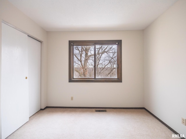 unfurnished bedroom featuring a closet and light carpet