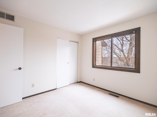 unfurnished bedroom featuring light carpet and a closet