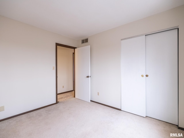 unfurnished bedroom featuring light carpet and a closet