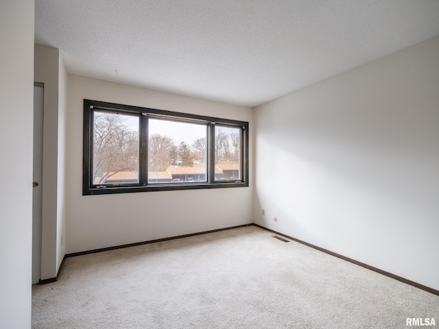 carpeted empty room featuring a textured ceiling