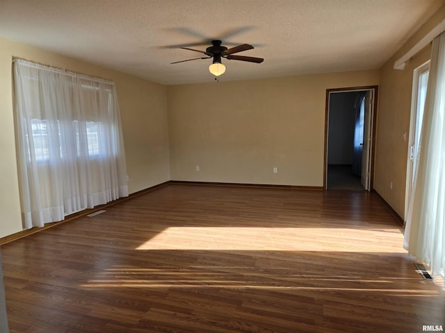 spare room featuring dark hardwood / wood-style flooring, ceiling fan, and a textured ceiling