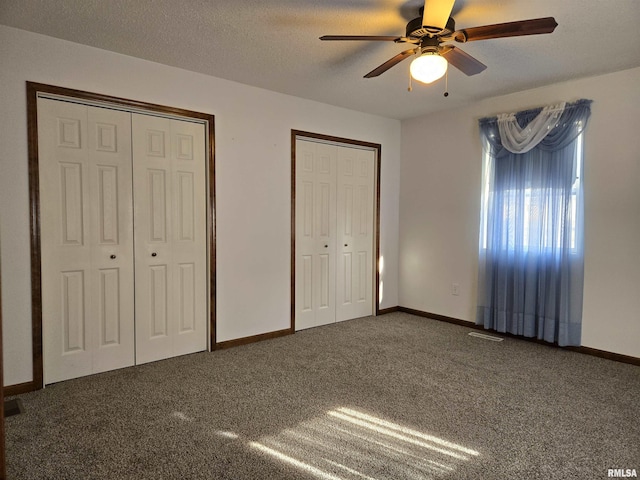 unfurnished bedroom with multiple closets, carpet, a textured ceiling, and ceiling fan