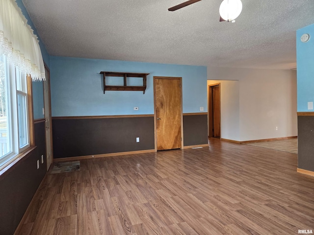 empty room with ceiling fan, hardwood / wood-style floors, and a textured ceiling