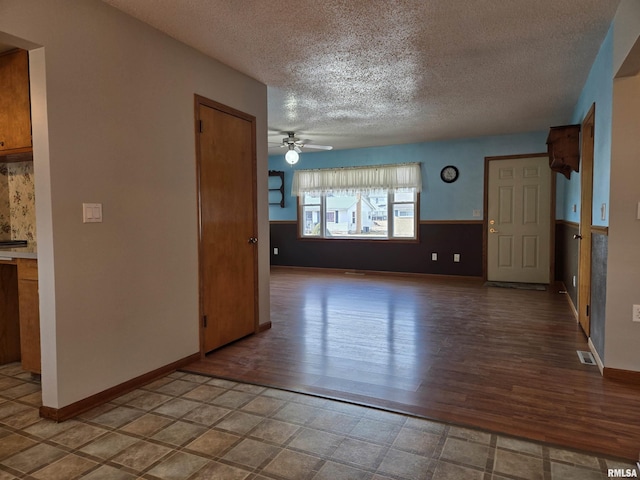 unfurnished living room with ceiling fan, hardwood / wood-style floors, and a textured ceiling