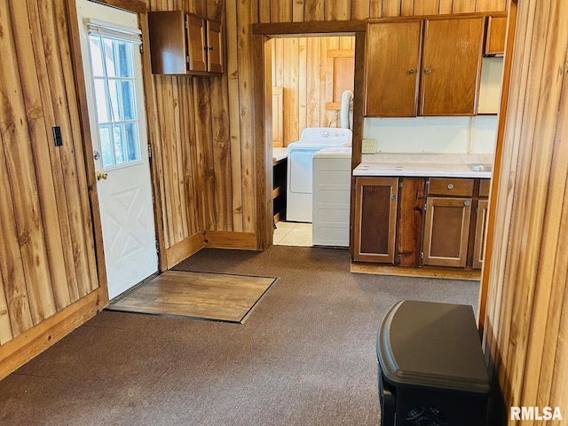 clothes washing area featuring cabinets, washing machine and dryer, and wood walls