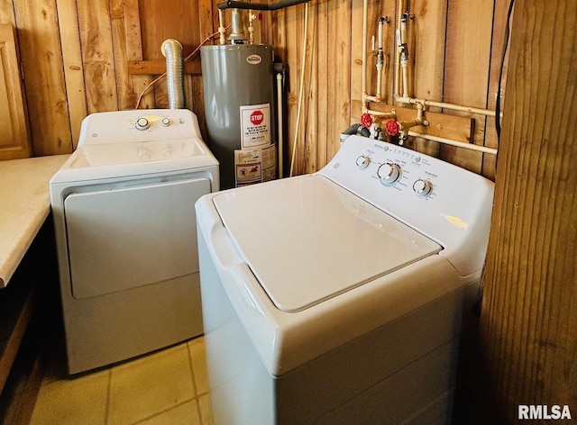 laundry area with light tile patterned flooring, washing machine and clothes dryer, and water heater