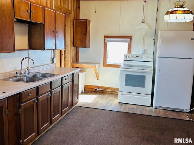 kitchen with hanging light fixtures, sink, white appliances, and dark carpet