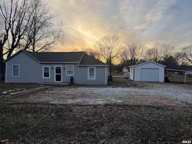 back house at dusk featuring a carport, a garage, and an outdoor structure