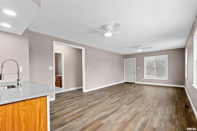 unfurnished living room featuring sink, hardwood / wood-style floors, and ceiling fan