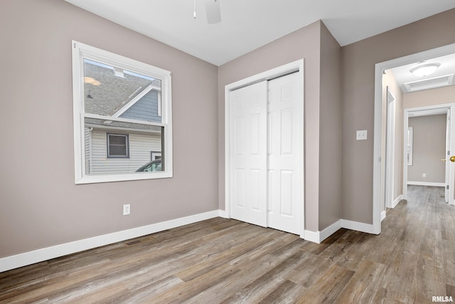 unfurnished bedroom featuring ceiling fan, light hardwood / wood-style floors, and a closet