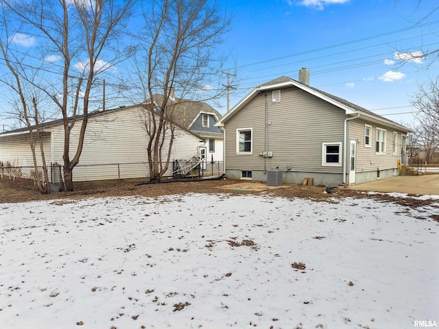 snow covered rear of property featuring central air condition unit