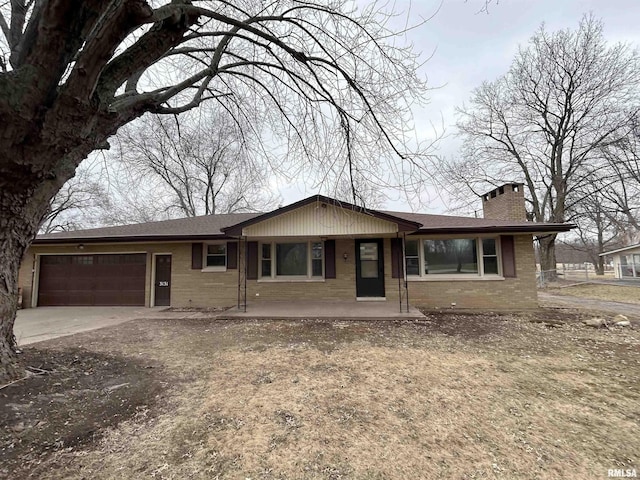 ranch-style home featuring a garage, concrete driveway, brick siding, and a chimney