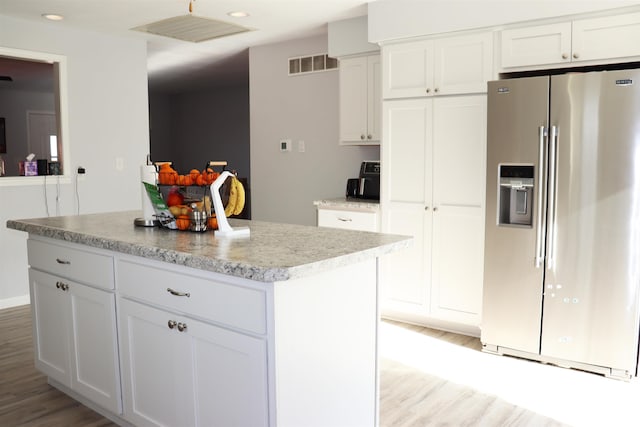 kitchen featuring white cabinetry, a kitchen island, high end fridge, and light wood-type flooring