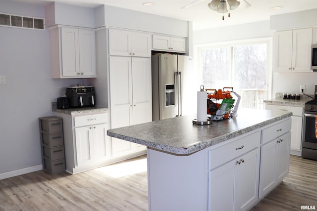 kitchen with appliances with stainless steel finishes, a center island, light wood-type flooring, ceiling fan, and white cabinets