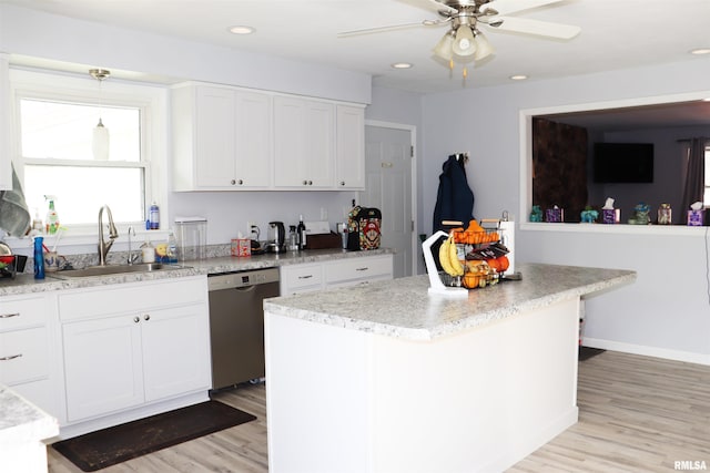 kitchen with stainless steel dishwasher, a kitchen island, sink, and white cabinetry