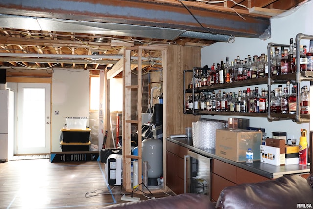 basement featuring hardwood / wood-style floors, white refrigerator, indoor bar, and beverage cooler